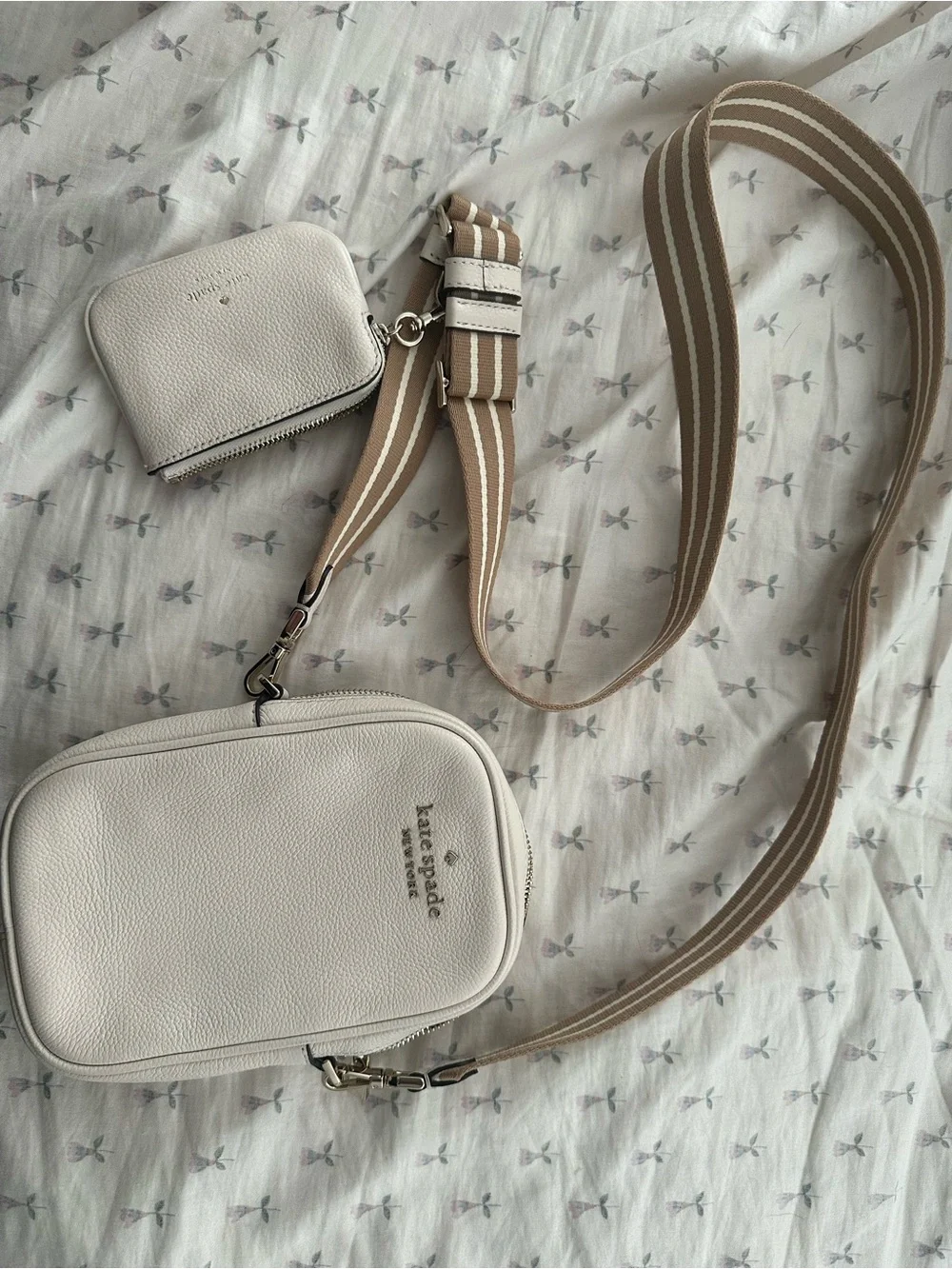 Kate Spade cream crossbody bag with tan striped strap and attached card holder